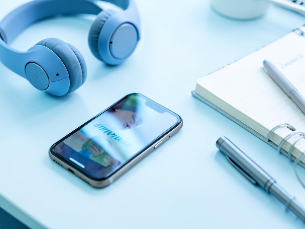 Celular virado para baixo ao lado de fones e caderno em mesa clara